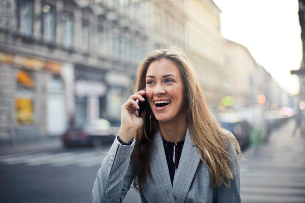 Une femme joyeuse discute au téléphone portable en marchant dans une rue animée de Budapest.